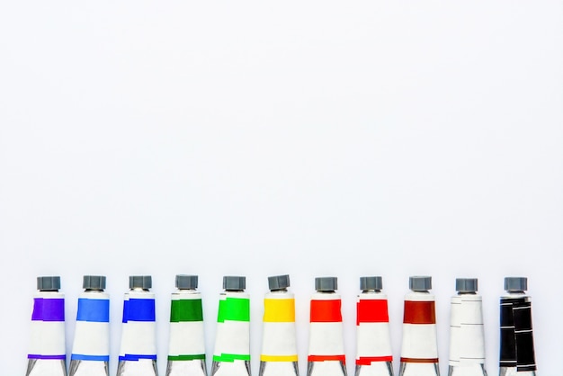 Top view set of colored tubes on white drawing pad