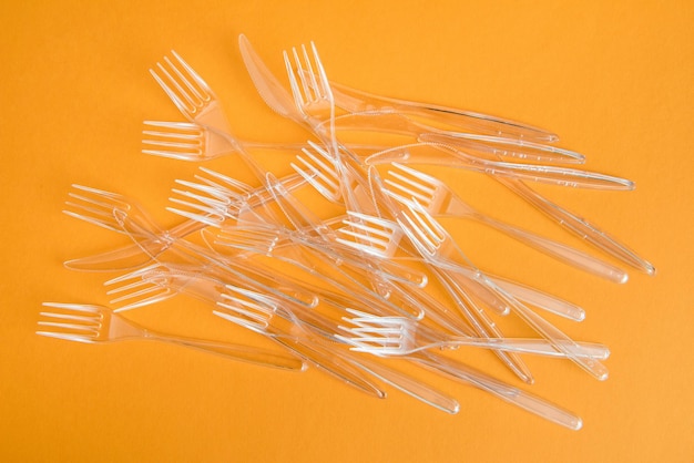 Top view of set of various plastic cutlery isolated on orange