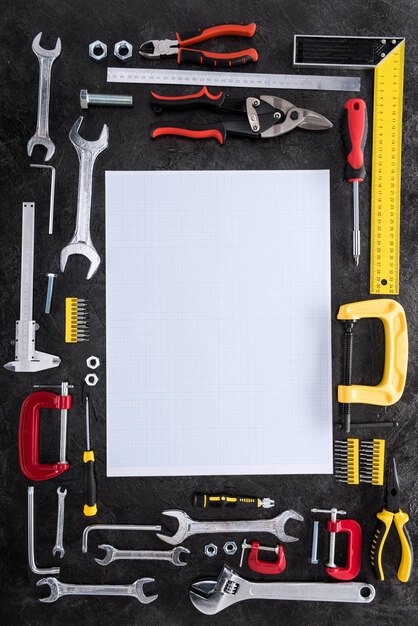 Photo top view of set of various work tools and blank paper on black