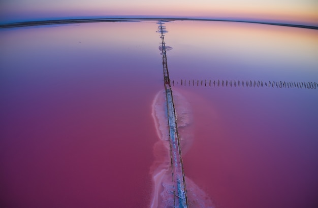 Вид сверху на блестящее соленое розовое озеро и тропу по нему