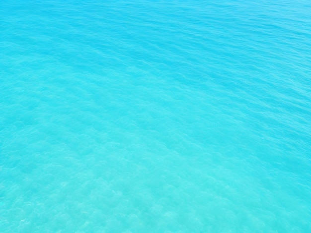 澄んだ青い海の水の光沢のある波の上から見る 青い背景