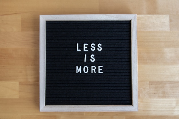 Top view shot of a black empty board on a wooden table with less ir more