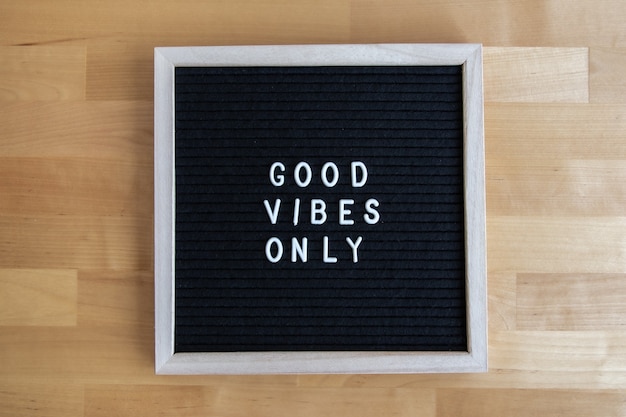 Top view shot of a blackboard with good vibes only quote on it at a wooden table