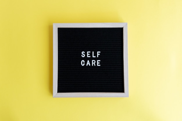 Top view shot of a blackboard with a self care massage on a yellow background