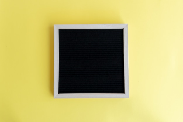 コピースペースと黄色の背景に木製フレームと空白の黒板の平面図のショット