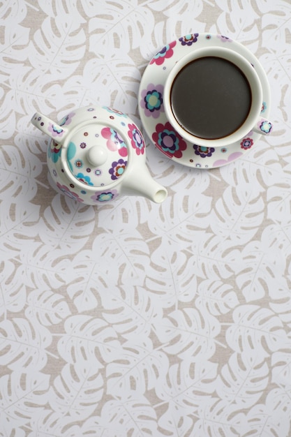 컵에 담긴 커피와 탁자 위에 있는 찻주전자의 상위 뷰 샷
