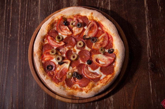 Vista dall'alto di una deliziosa pizza appena sfornata con affettati e peperoni