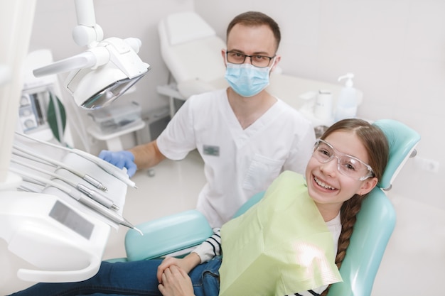 Top view shot of a dentist at his young patient in dental chair