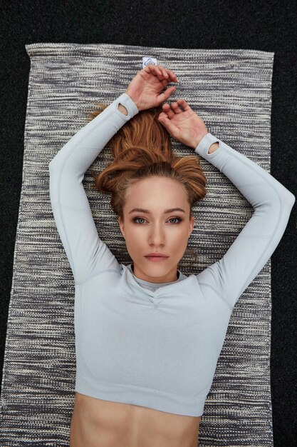 Top view shot of happy woman sitting on road after a morning run Fit woman on road taking a break after outdoor workout