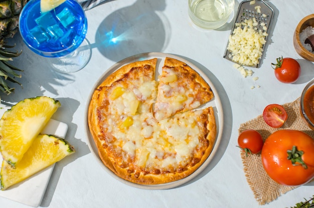 写真 おいしいおいしいハワイの伝統的なイタリアの地殻の薄いサクサクしたハムとパイナップルのピザがテーブルからチーズを伸ばしている三角形の部分のトップ ビュー ショット