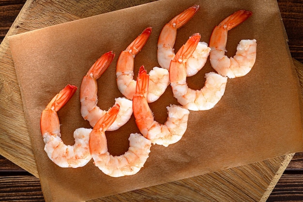 Photo top view of shrimps laid out on paper on wooden cutting board