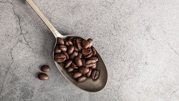 Photo top view of silver spoon with coffee beans