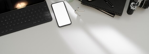 Top view of simple workspace with blank screen smartphone, tablet, office supples and copy space