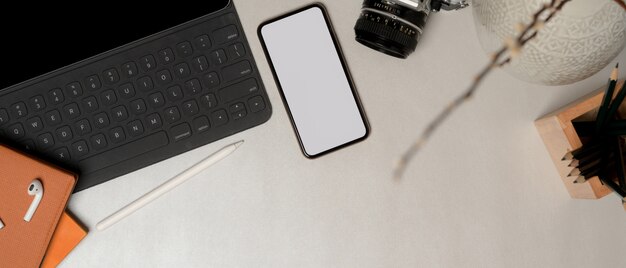 Top view of simple workspace with clipping path smartphone, office supplies and copy space on marble table