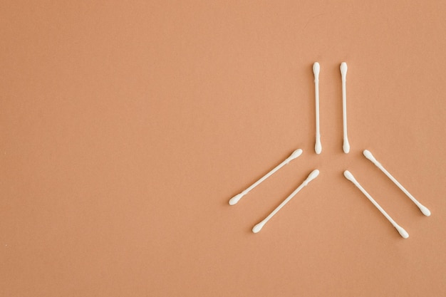 Photo top view of six ear sticks on beige background