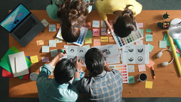 Top view of skilled designer holding logo while discussing with team symposium