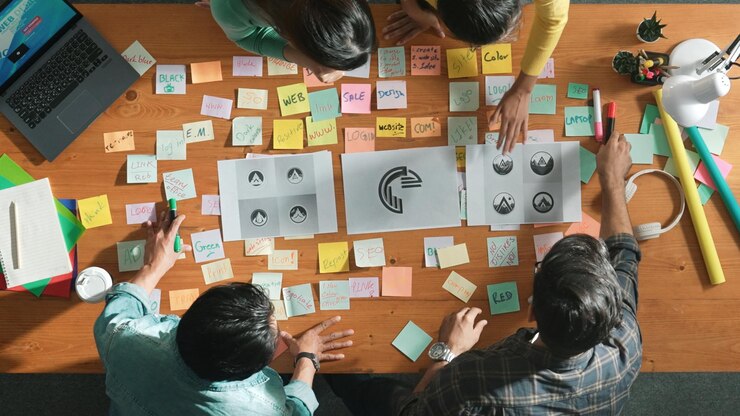 Photo top view of skilled designer holding logo while discussing with team symposium