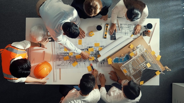 Foto vista dall'alto di un team di ingegneri qualificati che parlano mentre guardano l'alimentazione del piano