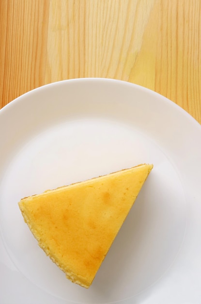 Top view of a slice of baked cheesecake on wooden background