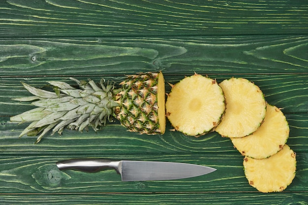 top view of sliced circles of ripe pineapple on green wooden table