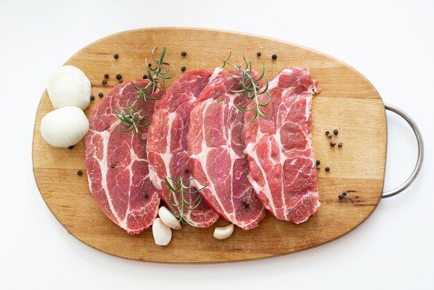 Top view on sliced raw pork meat with spices on wooden cutting board