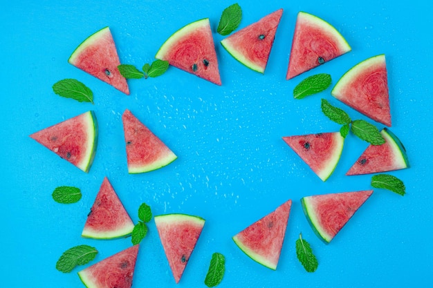 Top view sliced watermelon fruit with lots of mint leaves on old blue background