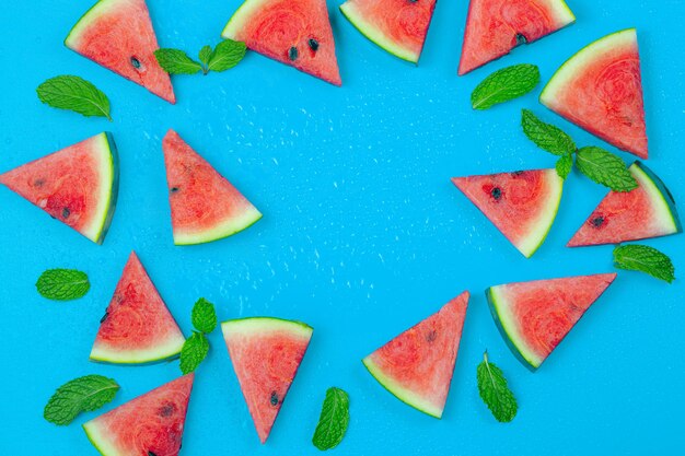 Top view sliced watermelon fruit with many mints leaves on the old blue wooden table