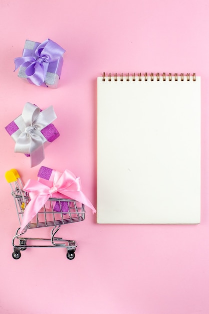 top view small gifts mini market trolley notepad on pink background