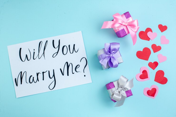 top view small gifts red and pink hearts will you marry me written on paper on blue background