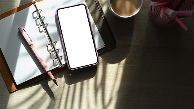 Photo top view smart phone, notebook and coffee cup on wooden table.