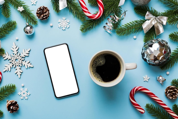 色付きの背景に熱いコーヒーのクリスマス装飾とスマート フォンのトップ ビュー