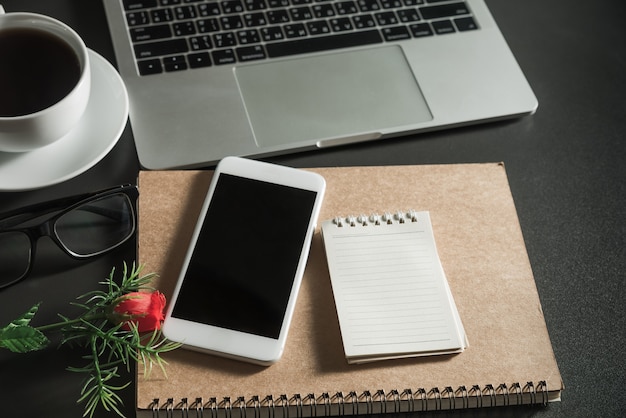 Photo top view of smartphone and computer, business workplace equipment with copy space on black