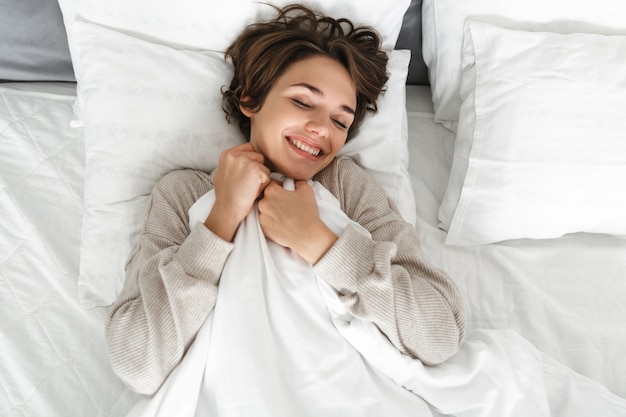 Top view of a smiling young girl relaxing in bed in the morning