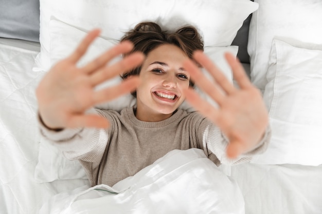 Vista dall'alto di una giovane ragazza sorridente rilassante a letto la mattina