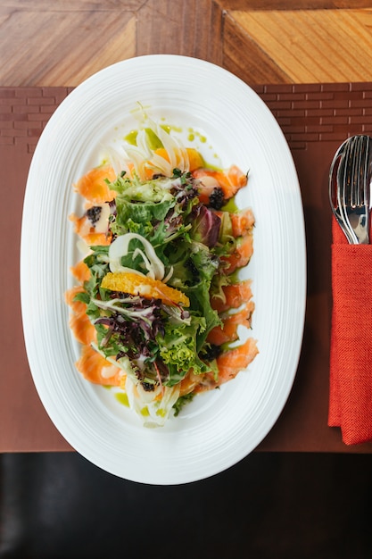 La vista dall'alto dell'insalata di pomelo di salmone affumicato include quercia verde, lattuga a foglia rossa e cipolla.