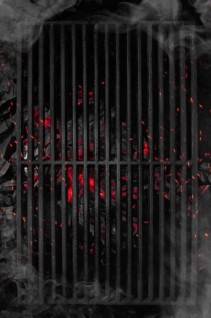 Photo top view of smouldering charcoals under black cast iron grill grate