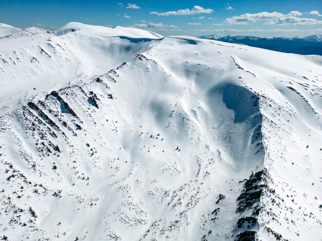 A top view of a snowy mountain range Kizly with a blue sky and clouds in the background