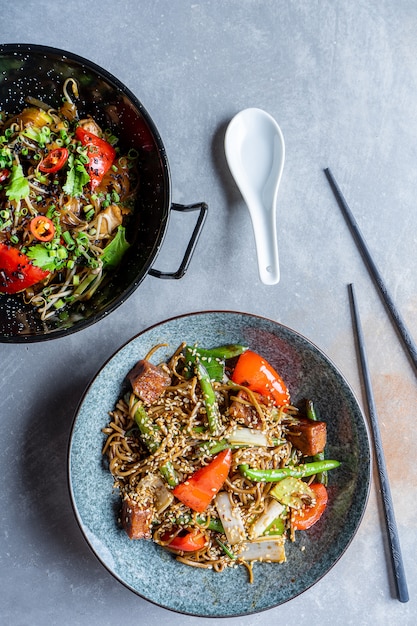 Foto vista dall'alto su spaghetti di soba con salsa agrodolce, verdure in ciotola grigia