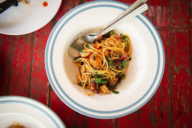 Top view of spaghetti with seafood and thai herb on wooden table