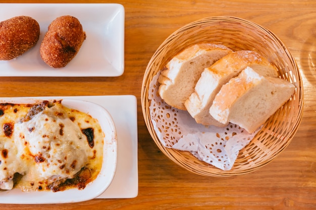 Lasagne와 파파스 Rellenas 바구니에 스페인어 신선한 구운 된 빵의 상위 뷰. 전채 요리.