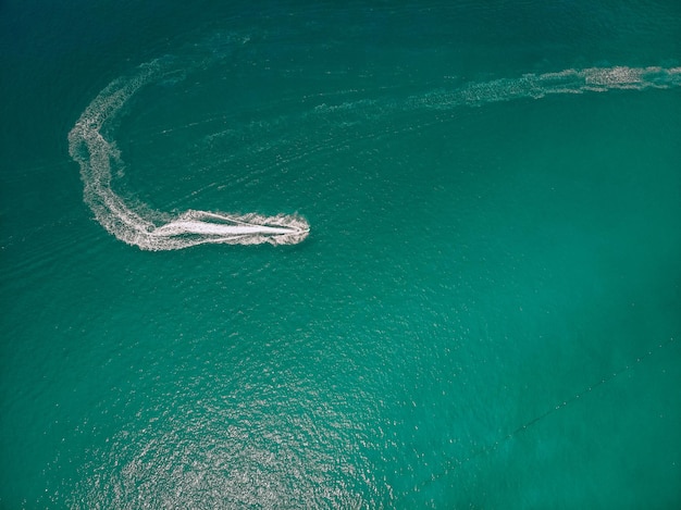 Top view of the speedboat, leaving trace on the surface of the blue water; vessels concept.