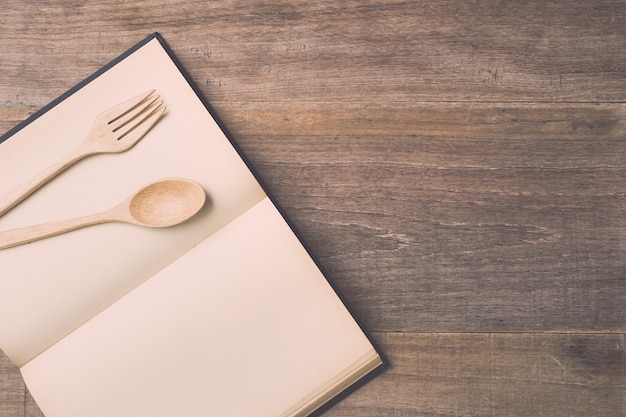 Top view spoon, fork and book on wooden plank background. Eating knowledge concept