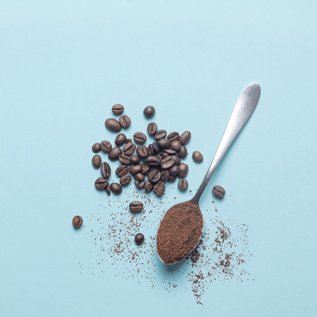 Top view of spoon with coffee and coffee beans isolated  on light blue background.