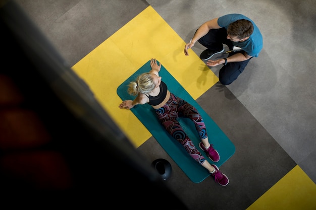 Top view at sporty woman exercises with assistance of her personal trainer