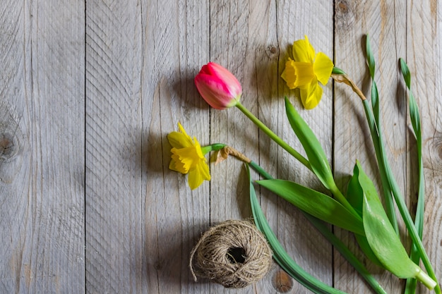 Top view of spring flowers bouquet. Yellow daffodils and pink tulip on wooden table. Copy space.