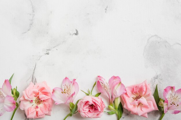 Photo top view of spring roses and orchids with marble background and copy space