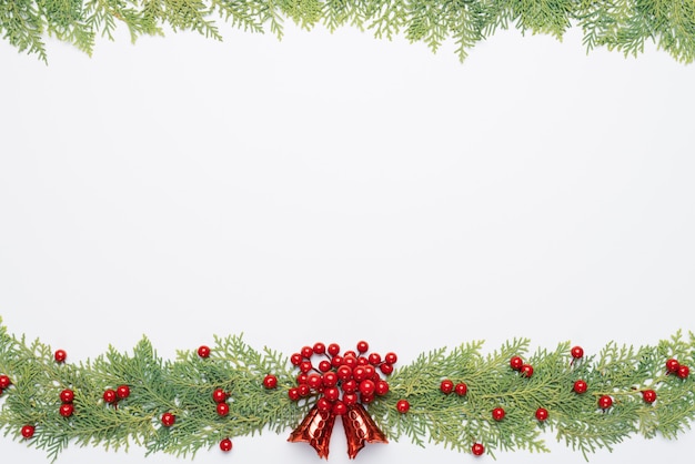 Top view of spruce branches, pine cones, red berries and bell on white background.