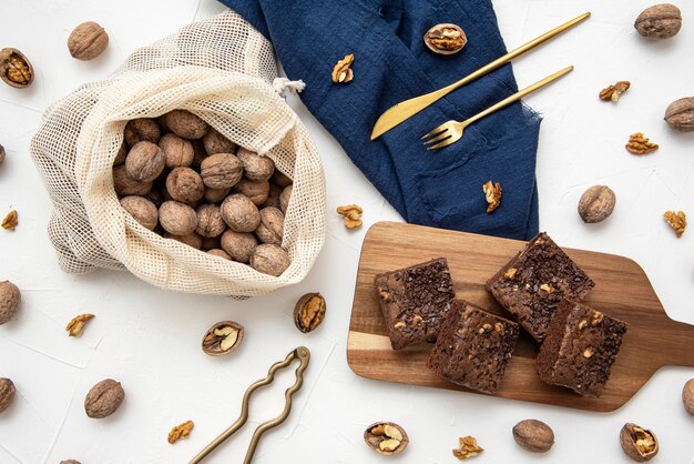 Top view of stacked brownies and nuts on white background