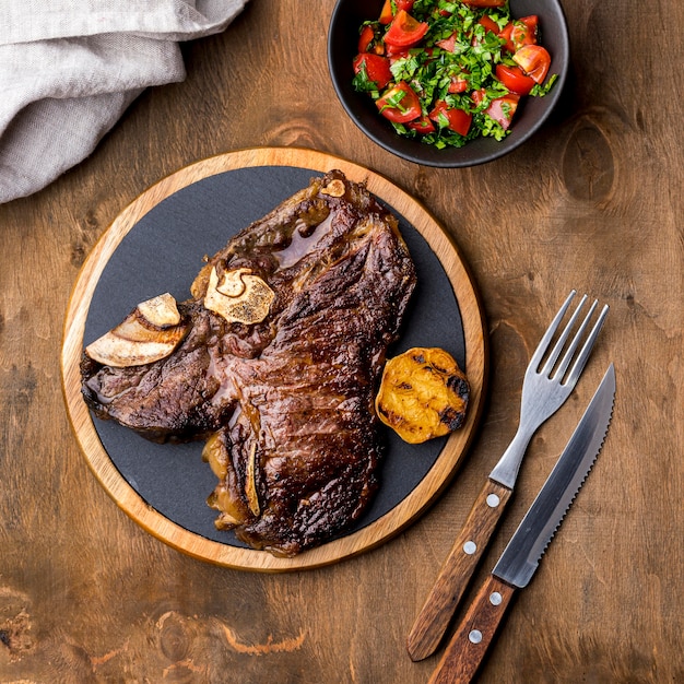 Top view of steak on plate with cutlery and salad