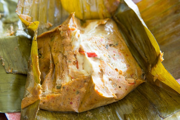 Photo top view of steamed fish in red curry mousse in the banana leaf, focus selective